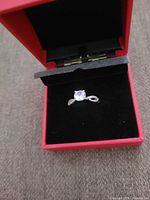 Ring in red box, center moissanite and gem-set band visible