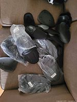 Multiple black motorcycle armor pads, some bagged, on sofa
