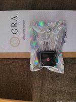 Gemstone in box on holographic sleeve atop GRA report
