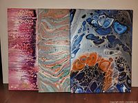 Front view of three abstract acrylic paintings