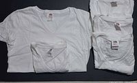 All five folded white V-neck T-shirts displayed