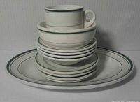 Stacked view of all 11 vitrified china pieces showing consistent white and green band pattern