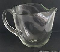 Side view showing full profile of clear glass pitcher with handle and spout
