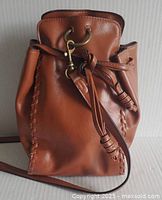 Front view of tan faux leather bucket bag showing hardware and drawstring