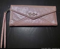 Front view of pink Jessica Simpson clutch showing JS logo and envelope flap