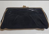 Front view of black suede and embossed leather clutch with gold-tone frame