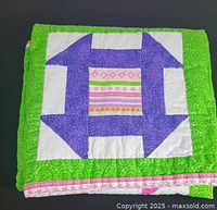 Folded quilt showing one churn-dash block with green border