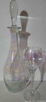 Decanter with stopper beside goblet showing size and iridescence