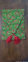 Scarf folded, showing cardinal and holly print with tassels