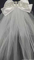 Close-up of satin bow and rhinestone BRIDE letters on veil crown