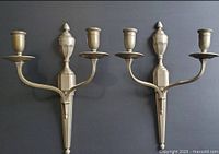 Both silver-tone two-arm wall sconces on dark background
