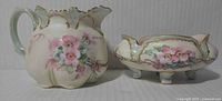 Front view of hand painted creamer and sugar bowl showing floral motif and gilt trim