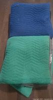 Folded blue and green moving blankets