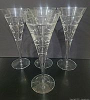 Four clear conical goblets displayed together