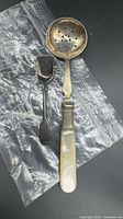 Top view of both spoons: sugar sifter with MOP handle and caddy spoon