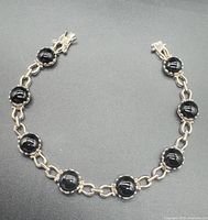 Full view of sterling silver bracelet showing eight black onyx stones and link design