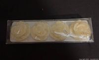 Top view of unopened package with four ivory rose-shaped candles
