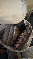 Open cosmetics bag with multiple eyeshadow palettes visible