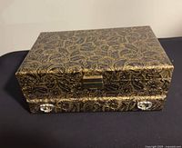 Closed jewelry box front view showing gold floral pattern and drawer knobs