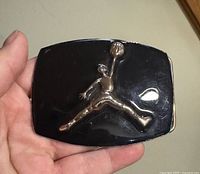Front of black belt buckle featuring silver Jumpman logo