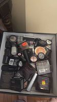 Top view of box filled with assorted unopened makeup