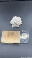 All three items: porcelain rose figurine, engraved metal box, angel token card