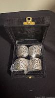 Open velvet box showing four napkin rings wrapped in plastic