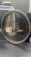 Full view of round silver-plated tray showing overall shape, gallery rim, tarnish