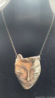 Full view of sculpted face pendant on chain