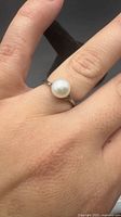 Ring worn on finger showing scale and pearl detail