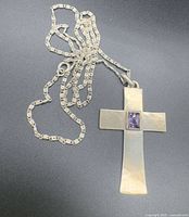 Full view of silver cross pendant attached to chain