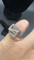 Ring on finger showing overlapping square design and dimple texture
