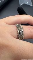 Ring on finger displaying woven chain link detail