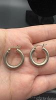 Pair of sterling silver hoop earrings on hand