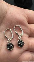 Both earrings showing front view of wire-wrapped black stones and leverbacks
