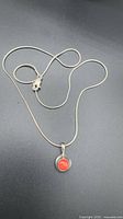 Full view of silver snake chain necklace with red coral pendant