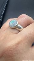 Full view of sterling silver ring on finger showing abalone shell cabochon