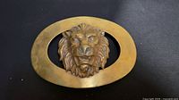 Front view of brass belt buckle with lion head in oval frame