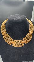Front view of articulated gold-tone filigree collar necklace on display bust