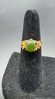 Front view of two-tone gold jade ring on display stand