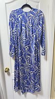 Front view of blue and cream leaf print Zara midi dress hanging on door