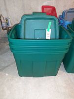 Front view of stacked green Rubbermaid totes showing lids and depth