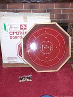 Front of Bentley crokinole board showing red playing surface and packaging