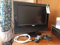 Front view of Digital Labs LCD TV on stand, remote and two cables placed in front
