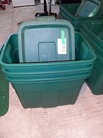 Front view of three nested green Rubbermaid storage totes with lid visible