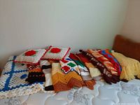Stack of crochet blankets and pillows on mattress