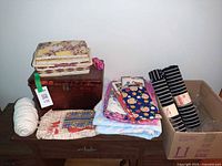 Overview of lot on dresser: sewing boxes, fabrics, yarn, striped fabric rolls, cardboard box