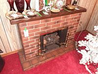 Front view of electric faux brick fireplace with accessories