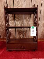 Front view of mahogany wall-mounted étagère showing three shelves and drawer