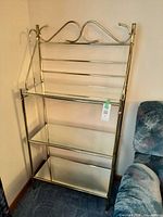 Full front view of brass-tone three-tier mirrored glass shelf